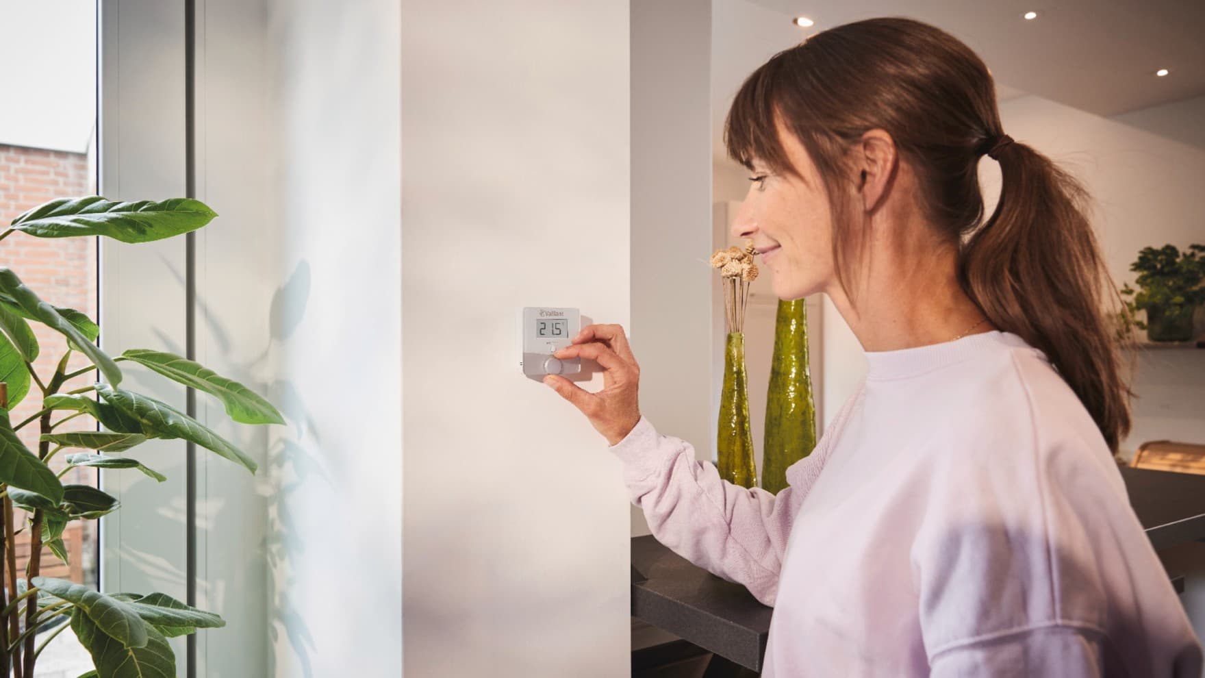 Жінка, яка використовує термостат Vaillant sensoROOM